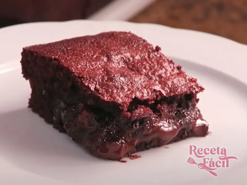 Porción de brownie de chocolate jugoso sobre plato blanco