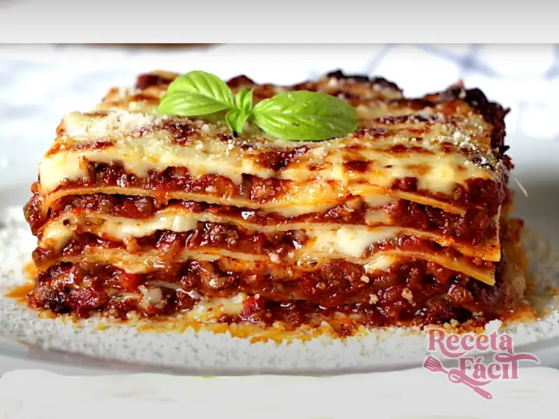 Primer plano de un trozo de lasaña humeante sobre un plato blanco con tenedor