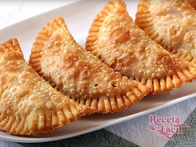 Primer plano de empanadillas crujientes recién hechas en plato blanco.